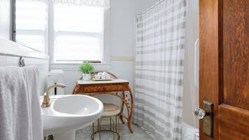 Un baño con lavamanos, tocador y puerta de madera.