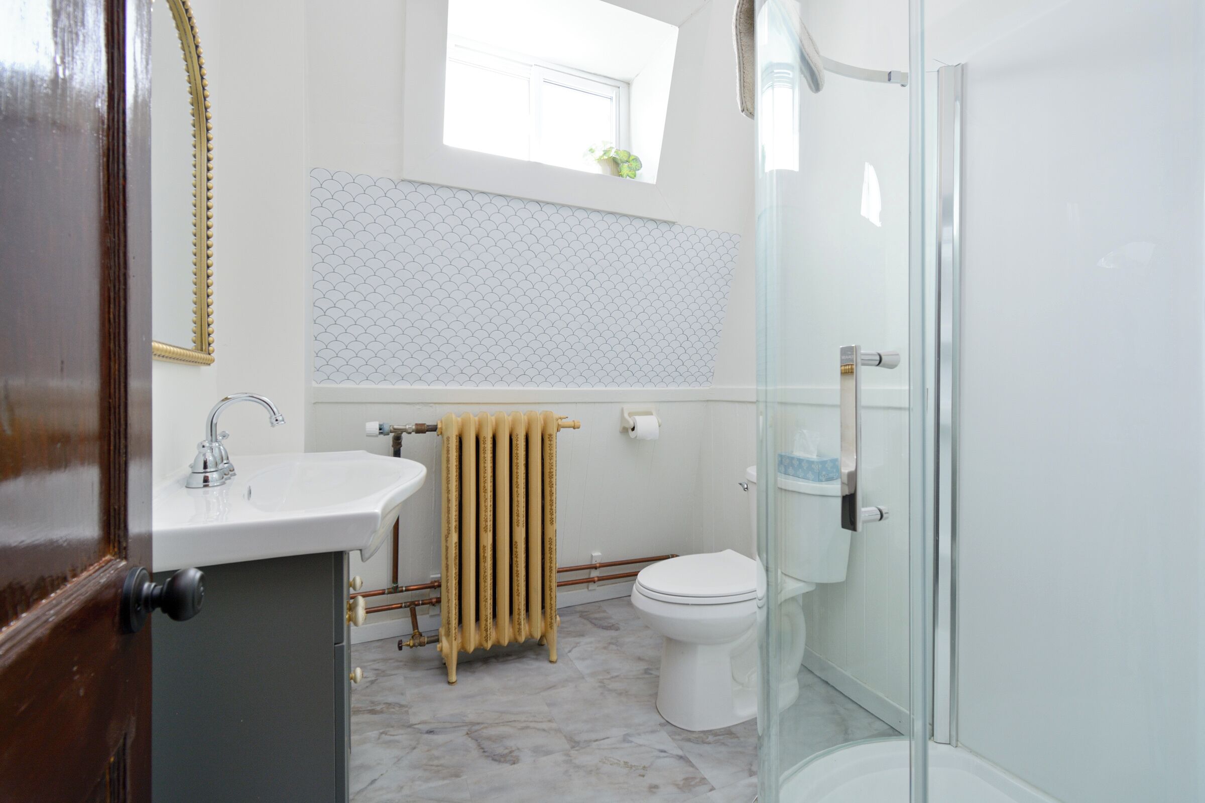 A bathroom with a white sink, toilet, and glass shower enclosure.