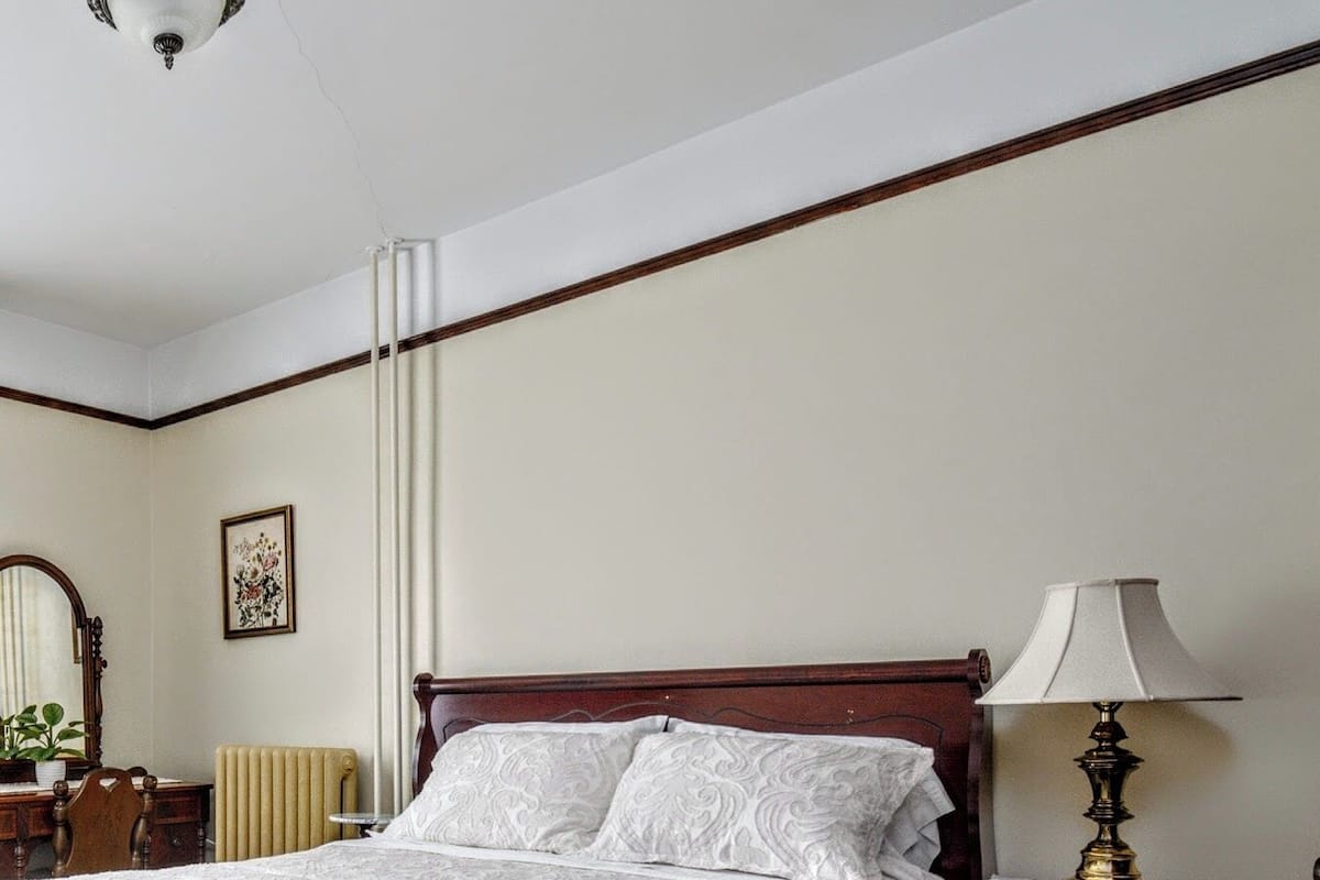 A neatly made bed with a white bedspread, a wooden headboard, and a bedside table with a lamp.