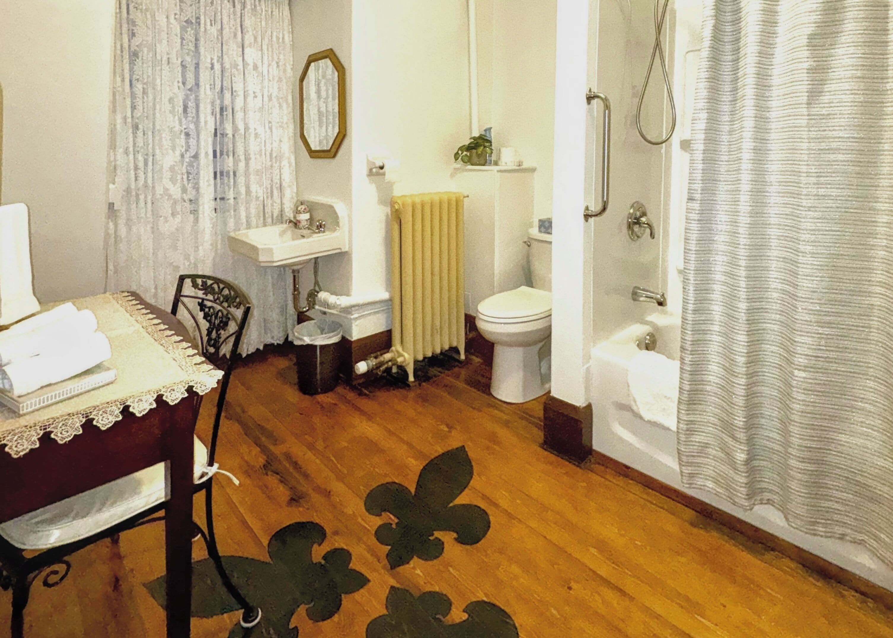 Une salle de bain avec un lavabo, des toilettes et une douche. Il y a un radiateur au-dessus des toilettes et une serviette sur le sol.