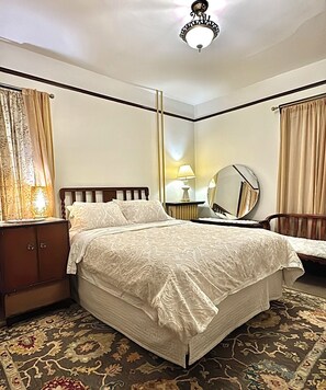 A hotel room with a bed, a nightstand, a lamp, a mirror, and a chair. - Royal Hotel Sydney (Sydney)