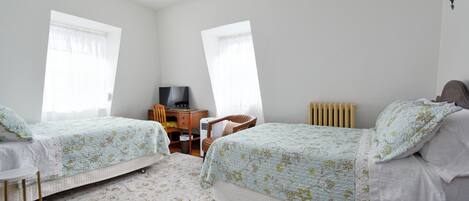A bedroom with two beds, a desk, and a chair.