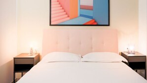 Quarto com uma cama grande, duas mesas de cabeceira e uma pintura abstrata emoldurada sobre a cama.