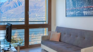 Uma sala de estar moderna com uma grande janela, um sofá cinza e uma pintura da paisagem urbana.