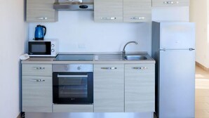 Uma cozinha moderna com armários de madeira clara, forno embutido, micro-ondas, pia e geladeira.