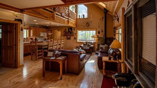A spacious living area with a wooden floor, a fireplace, and a large window. - Beautiful, Cozy and Quiet Home Nestled in an Aspen Grove (Jefferson)