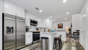 A modern kitchen with white cabinets, stainless steel appliances, and a central island. - Frisco Resort Style Home with Spa (Frisco)