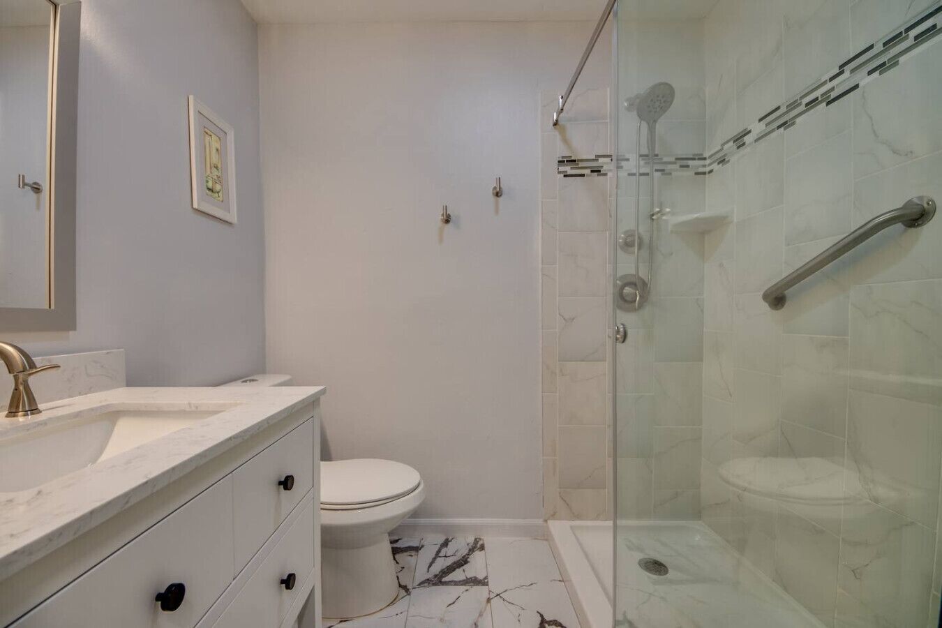 A bathroom with a marble sink, a toilet, and a glass-enclosed shower area.