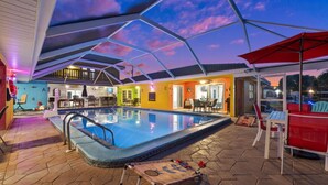 Una piscina interior con estructura de techo hexagonal, rodeada de diferentes zonas de estar y un espacio para comer.