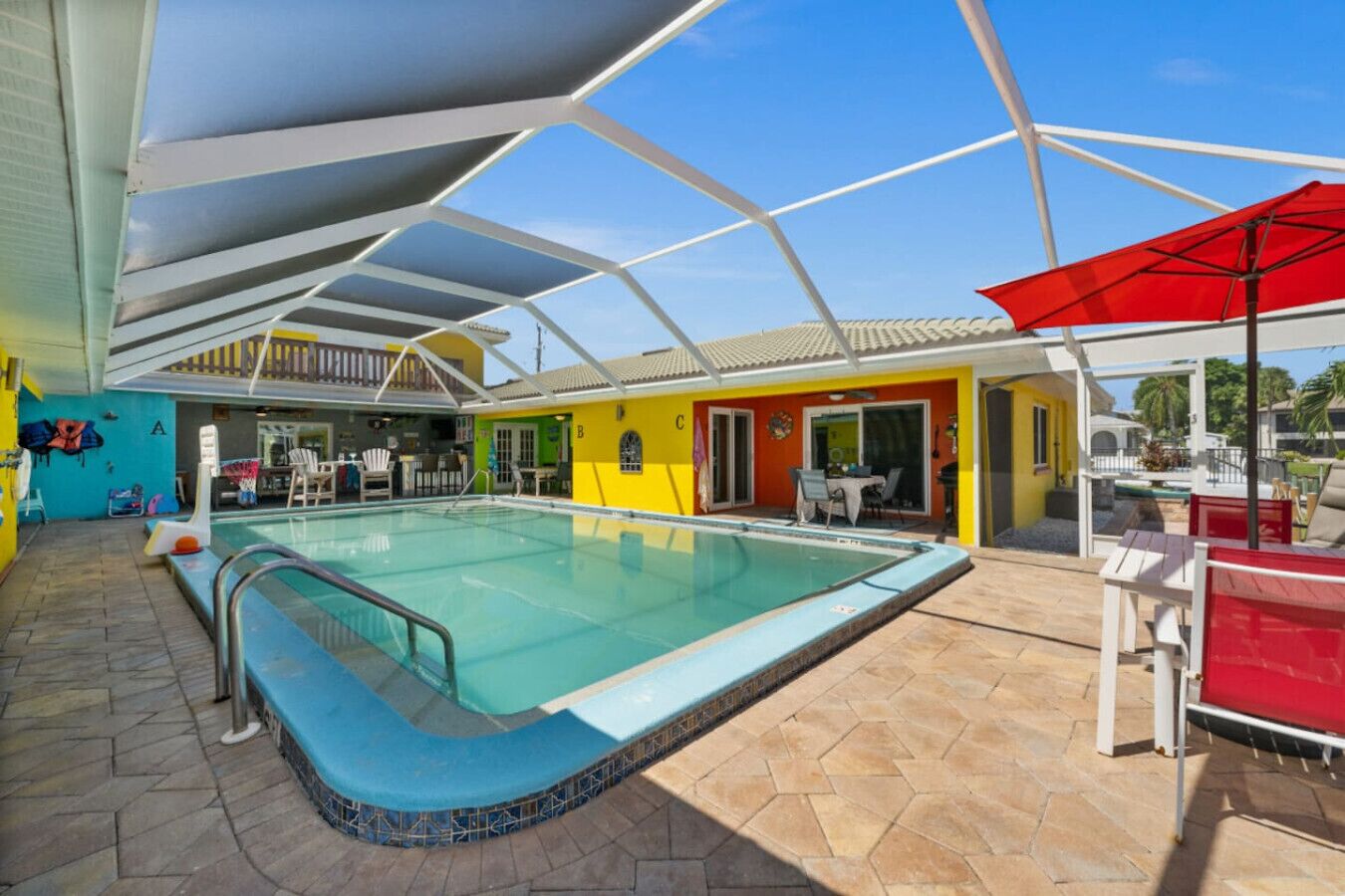 Una piscina interna con pavimento piastrellato e barriera in vetro. Sono presenti aree relax all'aperto con ombrelloni e un bar a bordo piscina.