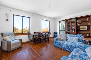 A spacious living area with a dining table, a sofa, a chair, and a bookshelf.