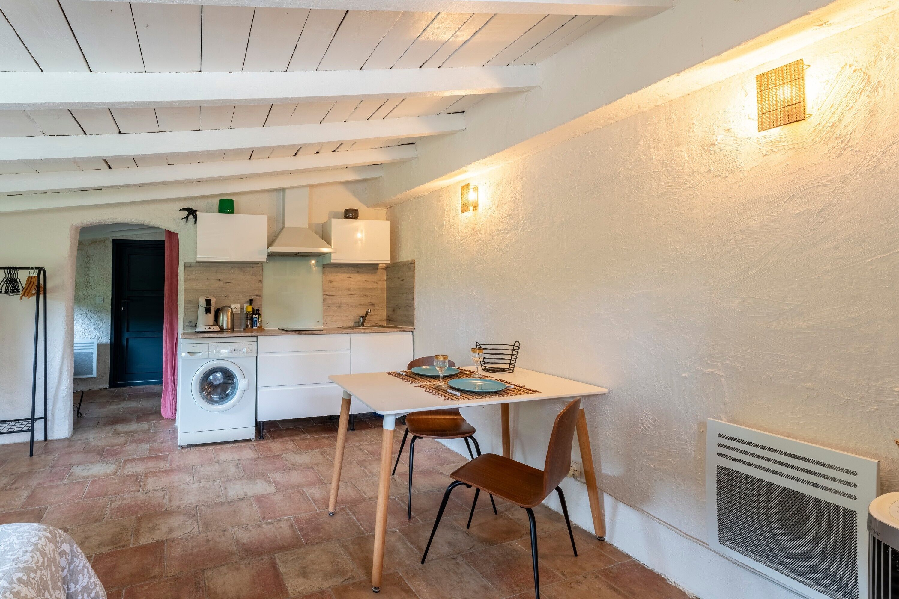 Een kleine keuken met een eethoek, een wasmachine en een radiator.