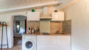 A compact kitchen with a washing machine, a sink, and a wooden countertop.