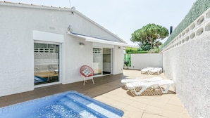 Una piscina amb gandules, un porxo cobert i un edifici blanc amb un garatge.