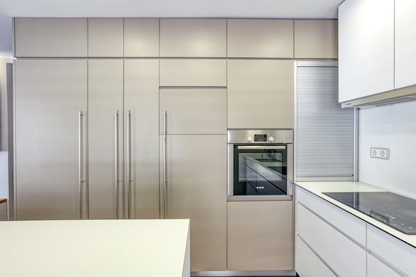 A modern kitchen with stainless steel appliances, a built-in oven, and a sleek countertop.