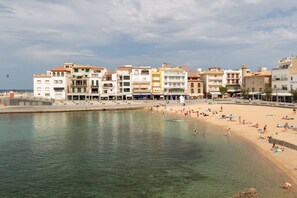 Un pueblo costero con playa, edificios y mar tranquilo.