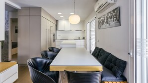 Cuina moderna amb una illa central, il·luminació empotrada i zona de menjador amb cadires i una banca.