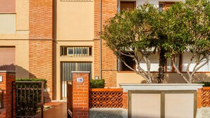 A residential building with a brick facade, a gated entrance, and a tree in front. - Apartment 'Casa Montecristo' with Air Conditioning, 50 Meters from the Sea (Castiglione della Pescaia)