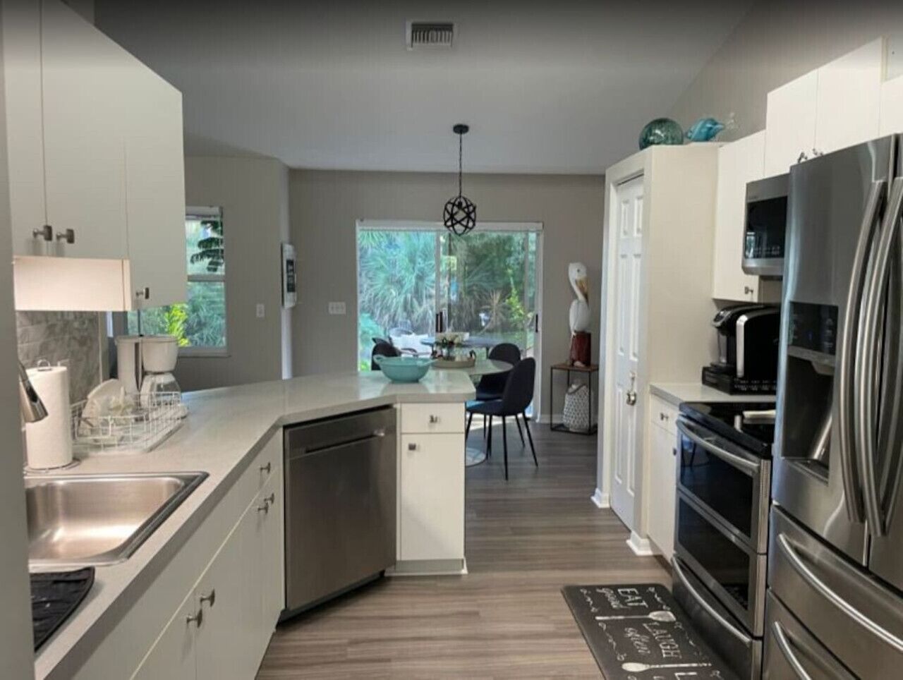 A modern kitchen with stainless steel appliances, a dishwasher, and a dining area with a table and chairs.