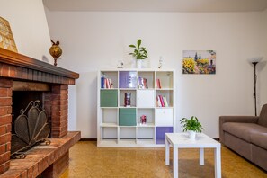 A living room with a fireplace, a bookshelf, a sofa, and a small table.