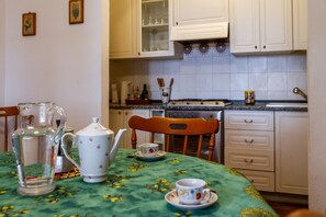 A kitchen with a table set for tea, a pitcher, and a teapot.