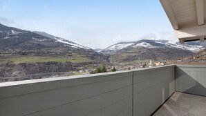 Un balcón con vistas a un valle y montañas.