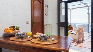 A wooden table with bowls and oranges, a window, and a view of the sea.