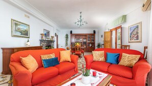 A living room with two red sofas, a coffee table with a tray, and a dining area with a wooden cabinet and chairs.