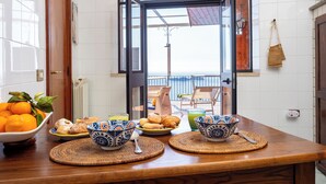 A breakfast table with a view of the balcony, a bowl of oranges, and a plate of pastries.