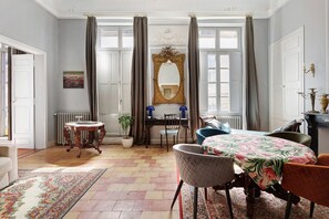 Una habitación con una mesa de comedor, sillas, un espejo y un radiador.