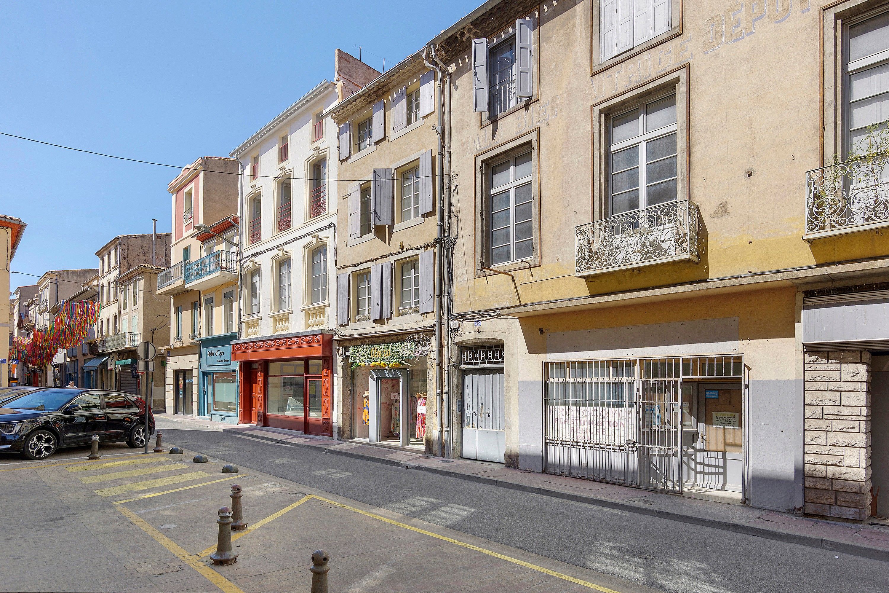 Una calle con edificios, tiendas y un coche estacionado.
