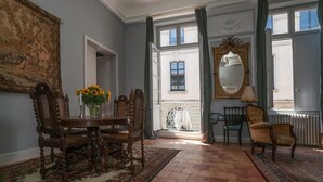A room with a dining table, chairs, a large mirror, and a view through an open door.