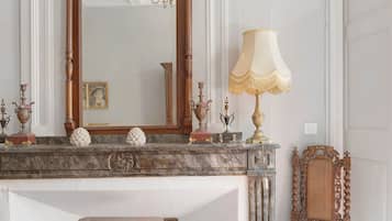 Une cheminée en marbre agrémentée de décorations raffinées, un grand miroir et une lampe classique.