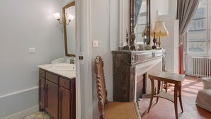 A bathroom with a marble sink, a mirror, a wooden chair, and a table. - Apartment 'La Suite Barbes' with Shared Garden, Balcony and Wi-Fi (Carcassonne)