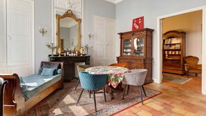 A room with a sofa, chairs, a table, a mirror, a cabinet, and a bookshelf. - Apartment 'La Suite Barbes' with Shared Garden, Balcony and Wi-Fi (Carcassonne)