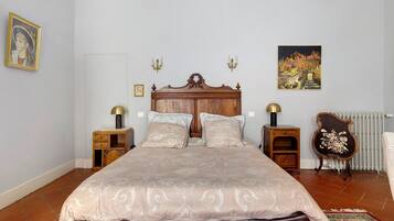 Een slaapkamer met een groot bed, twee nachtkastjes, een radiator en wandlampen.