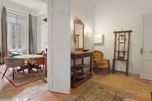 Una habitación con una cama, una mesa con sillas, un espejo y un armario de madera.