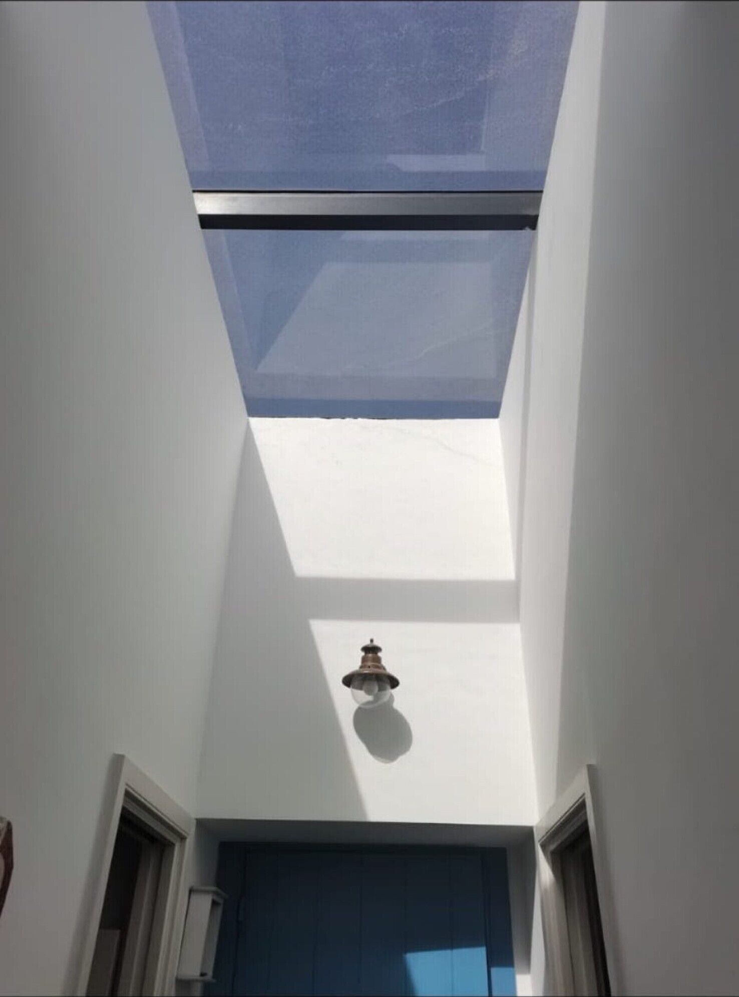 Un fanal amb vista al cel, una làmpada penjant del sostre i una porta a la part inferior.
