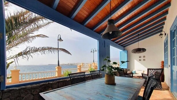 A dining area with a view of the sea, a stone wall, and a wooden ceiling. - Vacation Villa 'Delicias' with Sea View, Private Terrace and Wi-Fi (Taliarte)