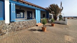 A building with blue doors and windows, a stone wall, and potted plants. - Vacation Villa 'Delicias' with Sea View, Private Terrace and Wi-Fi (Taliarte)