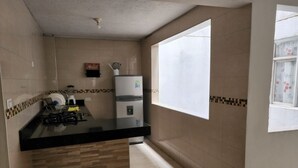 Una cocina con encimera negra, un refrigerador y una ventana.