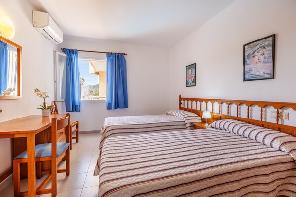 Una camera d'albergo con due letti, una scrivania in legno e una sedia.