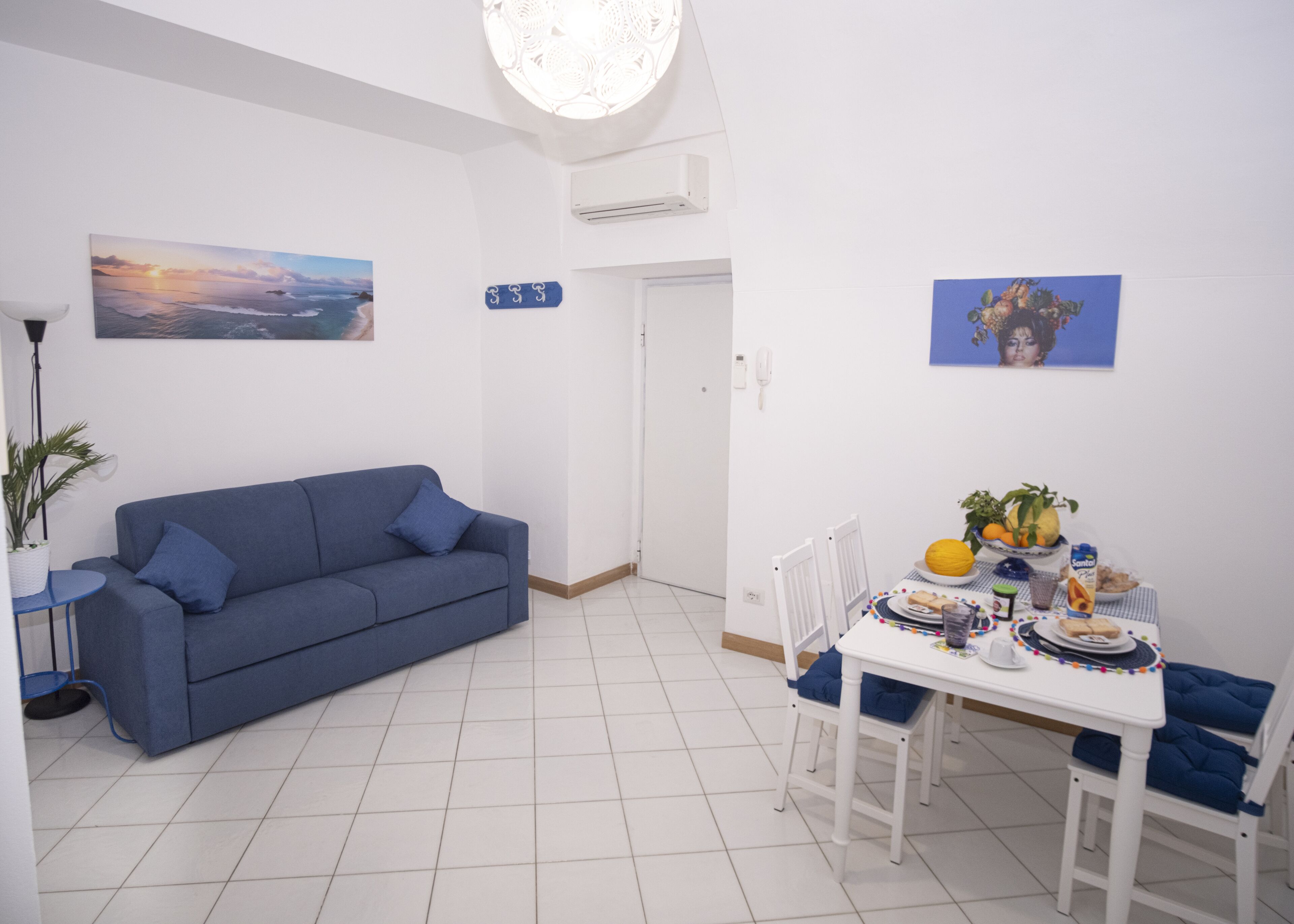 Un soggiorno moderno con un divano blu, un tavolo da pranzo con sedie e una lampada a sospensione.