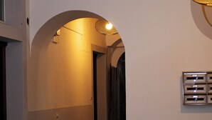 A narrow hallway with a vaulted ceiling, a wooden door frame, and a wall-mounted light fixture. - De Vivo Realty - Fortuna House (Sant'Agnello)