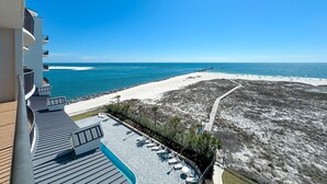 A high-rise hotel with a rooftop pool, a beach view, and a sandy area with palm trees. - Grand Pointe 613 | Beachfront | Resort Amenities | MyBeach Getaways (Orange Beach)