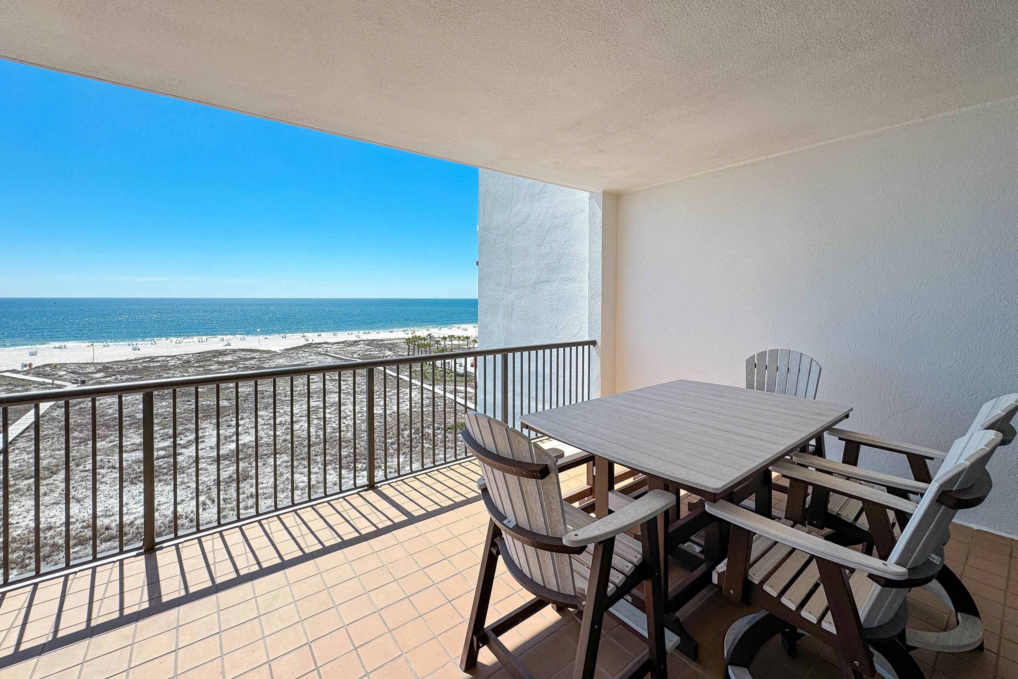 A balcony with a view of the beach and ocean.