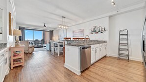 A spacious kitchen with wooden flooring, white cabinets, and a built-in dishwasher. - Grand Pointe 613 | Beachfront | Resort Amenities | MyBeach Getaways (Orange Beach)