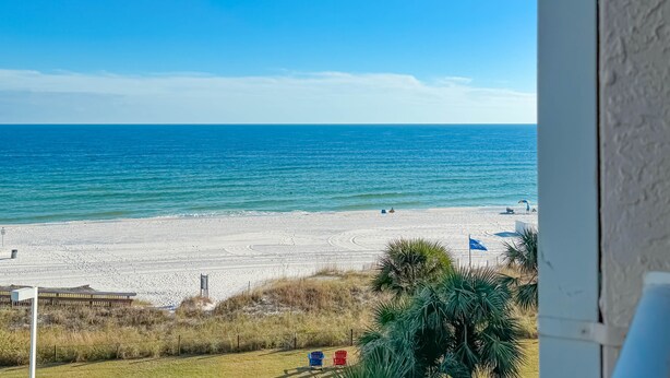 A beach view with a clear sky, a sandy beach, and a few people in the distance. - BEACHFRONT, TWO POOLS, PRIVATE BALCONY! (Orange Beach)