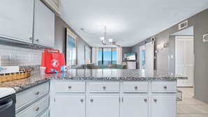 A modern kitchen with white cabinets, granite countertops, and a red shopping bag on the counter. - BEACHFRONT, TWO POOLS, PRIVATE BALCONY! (Orange Beach)