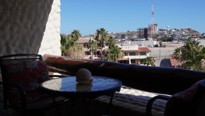 Ein Balkon mit Blick auf eine Küstenstadtlandschaft, darunter Gebäude und ein Baukran.